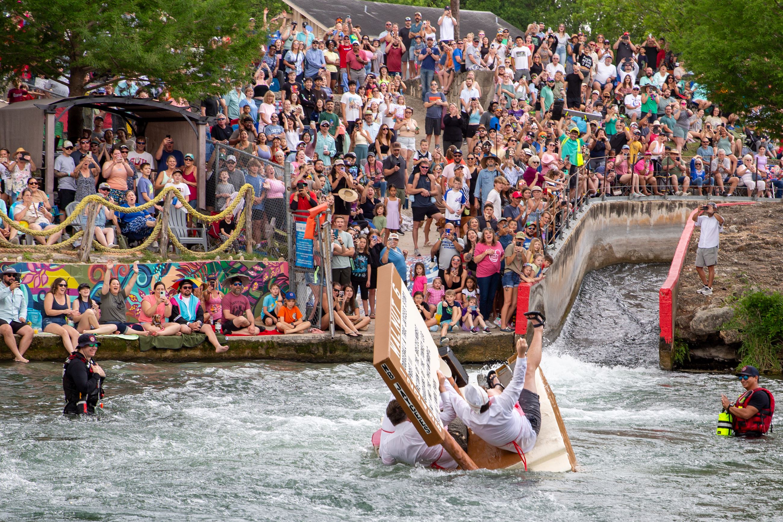 Thru the Chute Boat Race event With a Crowd of People at the New Braunfels City Tube Chute watching