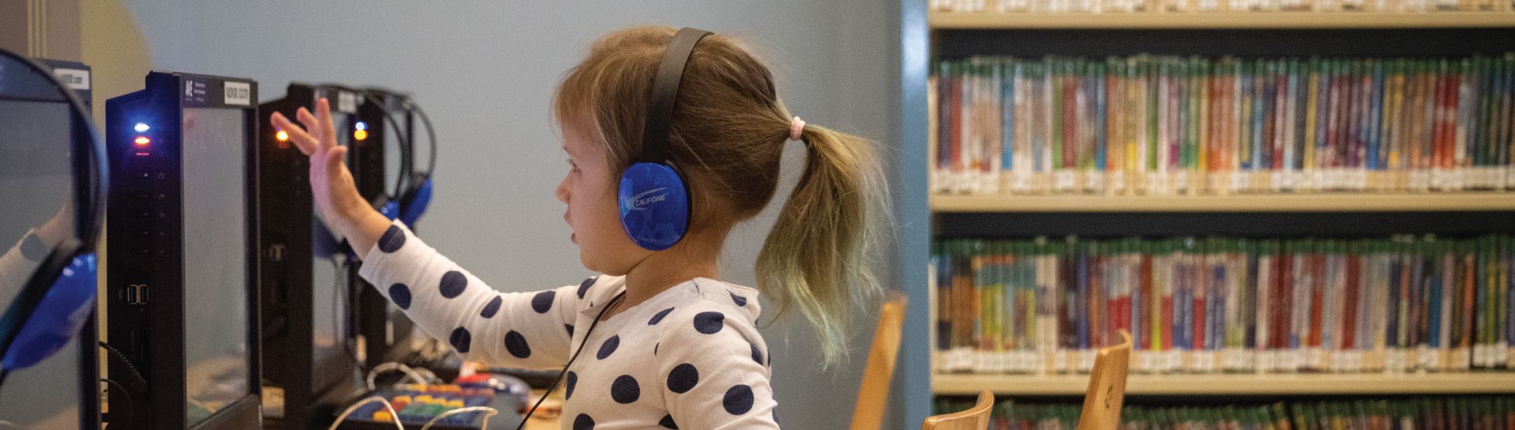 Little girl uses a touchscreen computer at the library