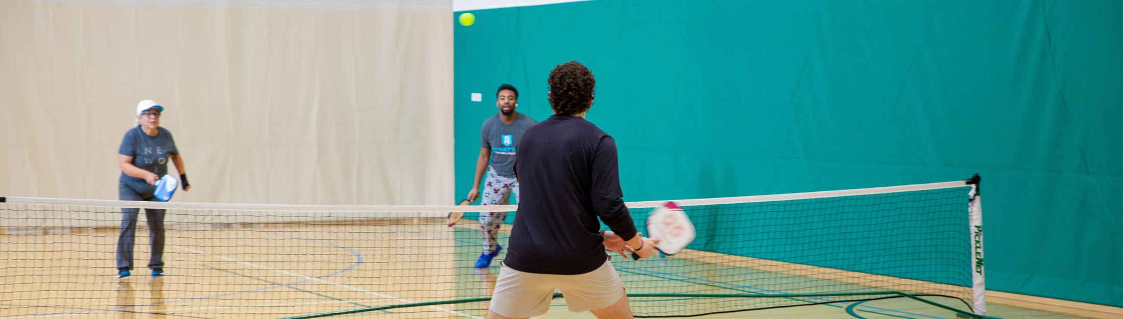Two people playing pickleball in the gym at Das Rec